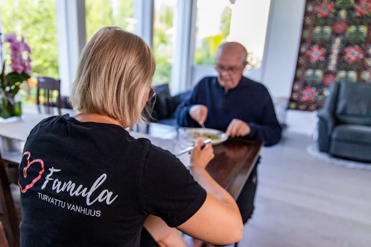 Perhe ja hoitaja syömässä yhdessä saman pöydän ääressä
